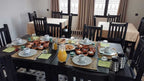 Riad La Luna breakfast setting with black wooden tables and chairs, orange juice, pastries, and small dishes on a patterned floor