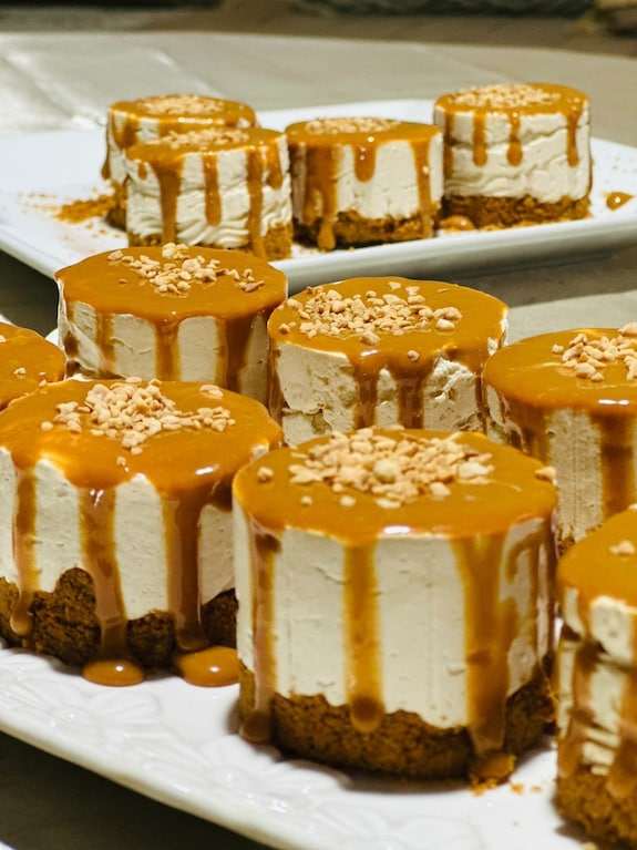 Riad La Luna caramel-topped mini cheesecakes with creamy layers on a white platter, garnished with crushed nuts