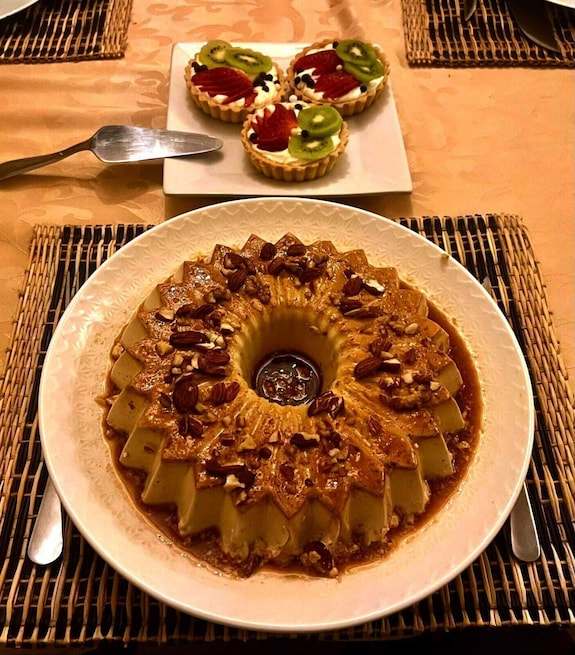 Riad La Luna dessert plate featuring a caramel flan topped with pecans and a plate of fruit tarts with kiwi and strawberry slices