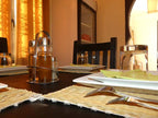 Riad La Luna dining table set with black chairs, beige woven placemats, white square plates, cutlery, and glasses in warm ambient light