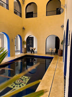 Riad La Luna indoor pool with yellow and blue walls, arched doorways, decorative tiles, and ceramic lanterns