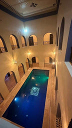 Indoor swimming pool at Riad La Luna featuring traditional Moroccan architecture with beige walls, arches, and decorative tile flooring