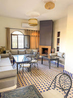 Riad La Luna living room with beige cushions, black wrought iron chairs, patterned tiled floor, and a modern fireplace