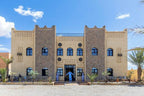 Riad La Luna traditional Moroccan three-story building with beige and stone facade, blue arched windows, and decorative elements