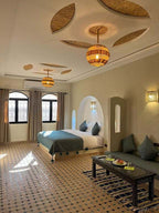 Riad La Luna spacious bedroom in Merzouga Morocco featuring beige walls, patterned tile floor, blue cushions and bedding