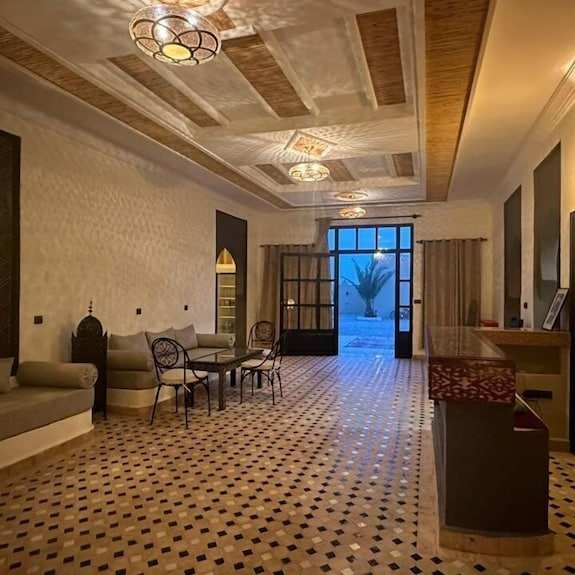Riad La Luna spacious Moroccan lounge with patterned tile floor, beige cushioned seating, wrought iron furniture, and ornate ceiling lights