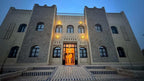 Riad La Luna traditional beige stone building in Merzouga Morocco with arched windows and warm exterior lights at dusk