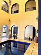 Riad La Luna courtyard with yellow and blue walls featuring arches and a small indoor pool with reflective water