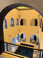 Riad La Luna interior courtyard with yellow walls, arched doorways, decorative black railings, and blue-tiled floor pool area