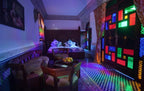 Riad Salam Fes bedroom with double beds, traditional Moroccan wood furniture, patterned tile floor, and colorful stained glass windows