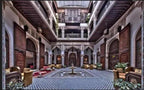 Riad Salam Fes spacious Moroccan courtyard with patterned tile flooring, carved wooden doors, arched design, and seating
