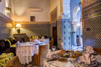 Riad Salam Fes dining area with traditional Moroccan blue and white mosaic tiles, round tables set with white linens and dishes