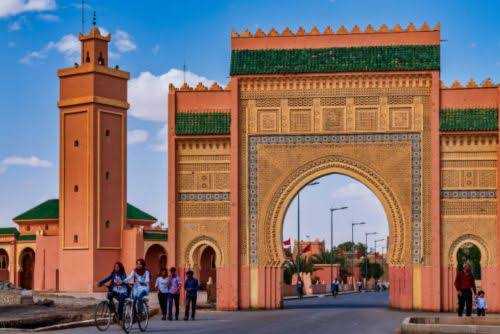 Historic Moroccan city gate in warm terracotta and green tile with arched doorways and intricate geometric patterns during Rissani Market Day Tour.