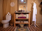 Royal Luxury Camp bathroom with beige canvas walls, toilet, wooden vanity with towels, mirror, and a white robe on a wooden rack