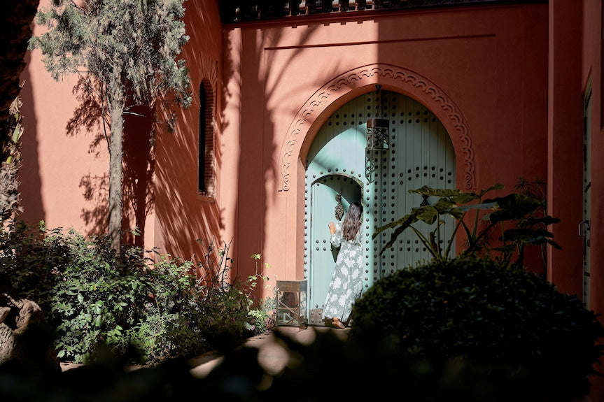 Royal Mansour Marrakech arched doorway in terracotta walls with green studded wooden door surrounded by greenery