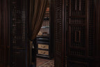 Dark wooden carved doors partially open to a room with traditional Moroccan design and woven baskets inside, evoking Royal Mansour Marrakech