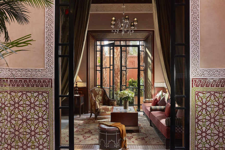 Elegant Moroccan riad interior at Royal Mansour Marrakech featuring intricate tilework, carved wood, upholstered furniture, and natural light