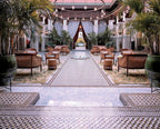 Royal Mansour Marrakech courtyard with intricate mosaic tile flooring, elegant brown leather chairs, palm plants, and hanging lanterns