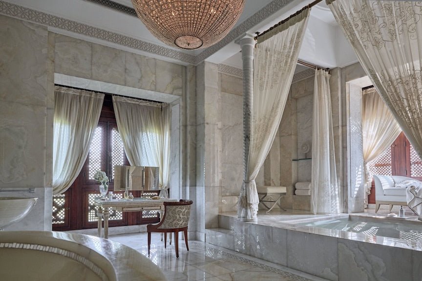 Royal Mansour Marrakech luxury bathroom with white marble, sheer curtains, elegant chair, and intricate chandelier