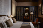 Luxury bedroom at Royal Mansour Marrakech featuring white bedding, brown cushions, intricate wood paneling, and ornate dark doors
