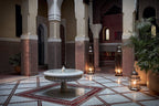 Royal Mansour Marrakech courtyard featuring intricate Moroccan tilework, arched columns, a central stone fountain, and traditional lanterns