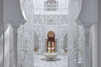 Royal Mansour Marrakech interior with white intricate Moroccan latticework, marble columns, arches, and central stone fountain