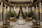 Royal Mansour Marrakech lounge area with traditional Moroccan tilework, wooden ceiling, hanging lanterns, curtains, and rattan armchairs