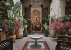 Royal Mansour Marrakech courtyard with traditional Moroccan tile floor, central stone fountain, lush potted plants, and ornate carved wooden doors