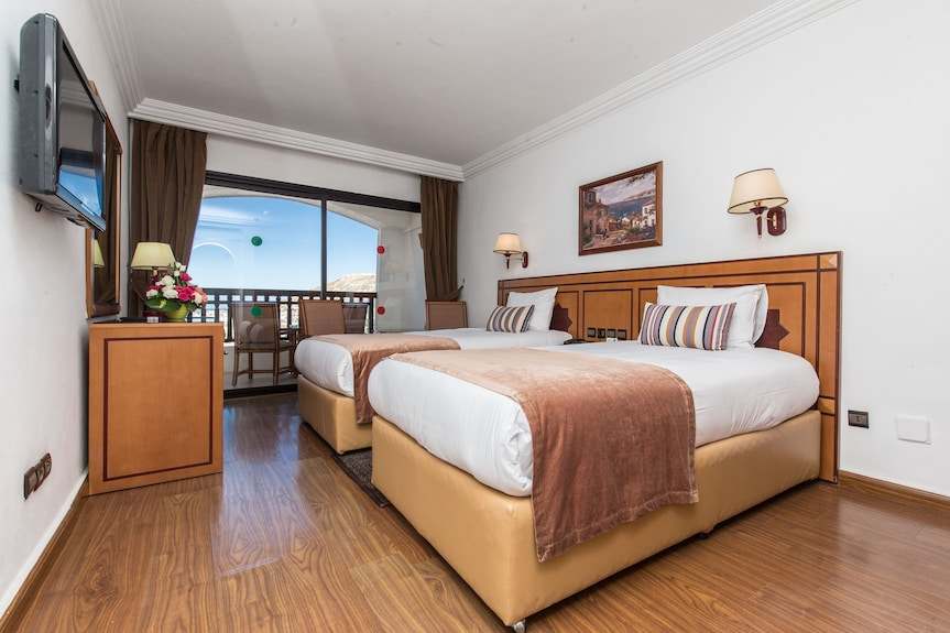 Royal Mirage Agadir hotel room with two twin beds, white linens, striped pillows, wood furnishings and balcony