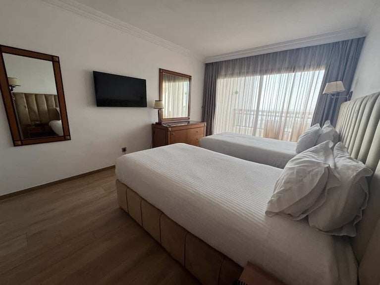 Royal Mirage Agadir hotel twin room with two white beds, upholstered headboards, wall-mounted TV and wooden furniture