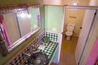 Bathroom at Sahara Garden Luxury Camp featuring green and white patterned tiled countertop, black stone sink, decorated mirror, and separate toilet area
