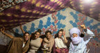 Sahara Wild Camp group of five people in colorful traditional tent with patterned fabric walls and ceiling smiling and posing