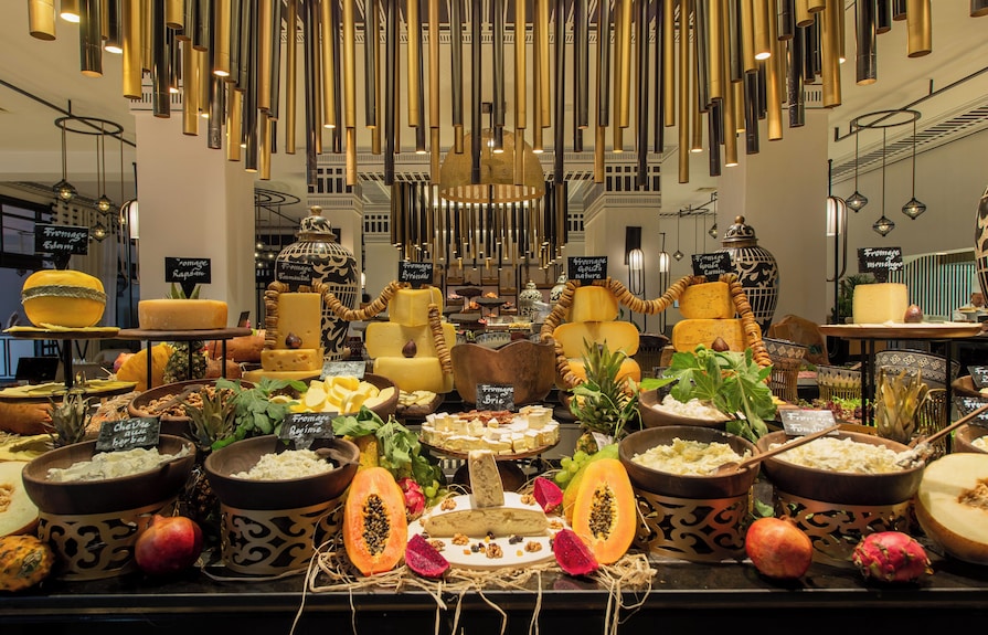 Cheese and fruit buffet display with a variety of cheeses, papayas, pomegranates, and decorative bowls at Sofitel Marrakech Palais Imperial & Spa
