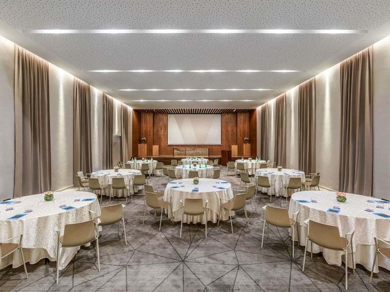 Sofitel Marrakech Palais Imperial & Spa elegant conference room with round tables, beige chairs, carpeted floor, and wall curtains