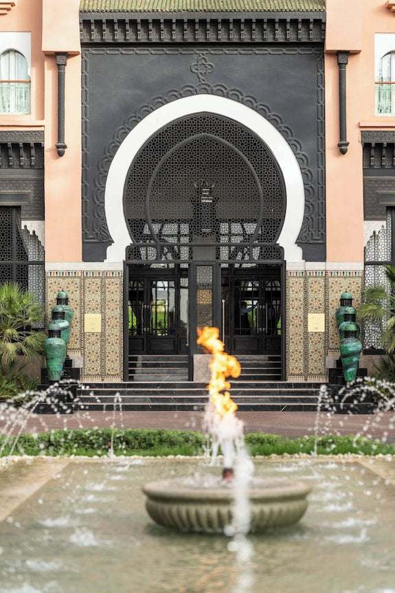 Sofitel Marrakech Palais Imperial & Spa entrance with Moroccan architectural details, intricate tilework, black arch doorway, and a central fountain with fire feature