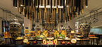 Gourmet buffet display with various cheeses, fruits, and Moroccan decorative urns under modern hanging lights at Sofitel Marrakech Palais Imperial & Spa