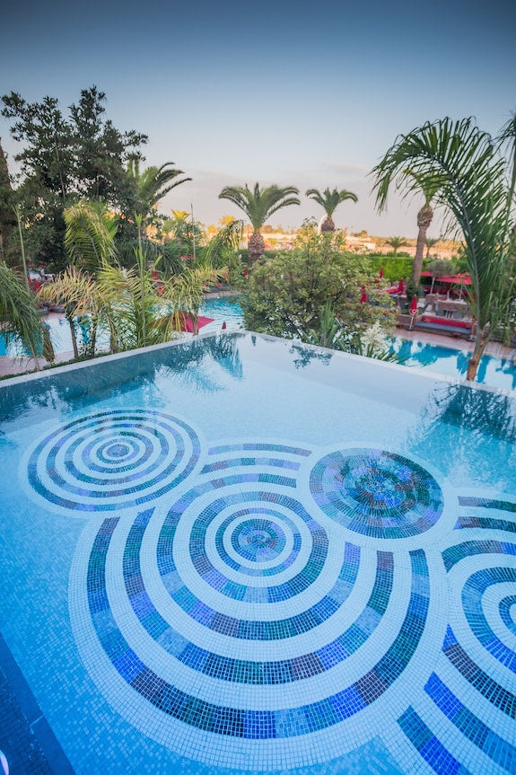 Sofitel Marrakech Palais Imperial & Spa outdoor infinity pool with blue mosaic circular patterns surrounded by palm trees and lush greenery