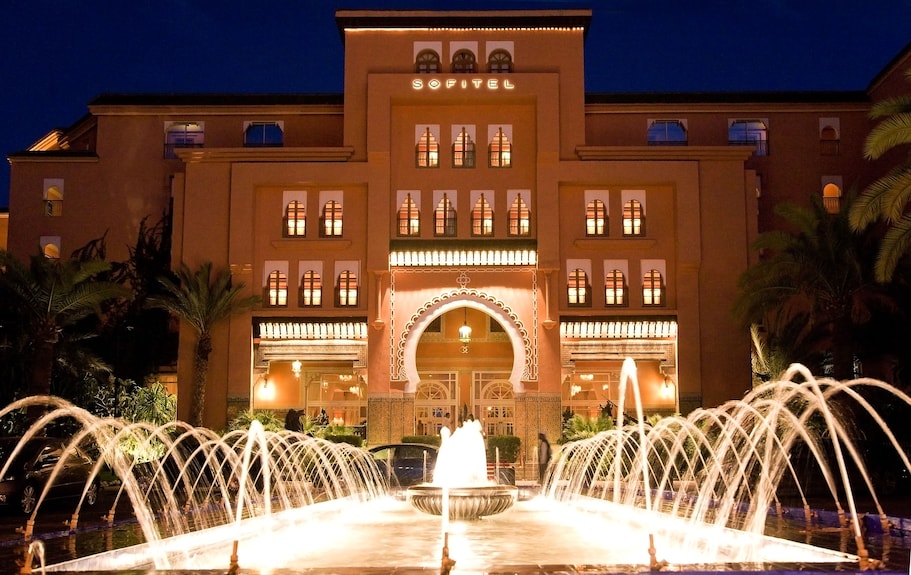 Sofitel Marrakech Palais Imperial & Spa luxury hotel building illuminated at night with arched entrance and water fountains in front