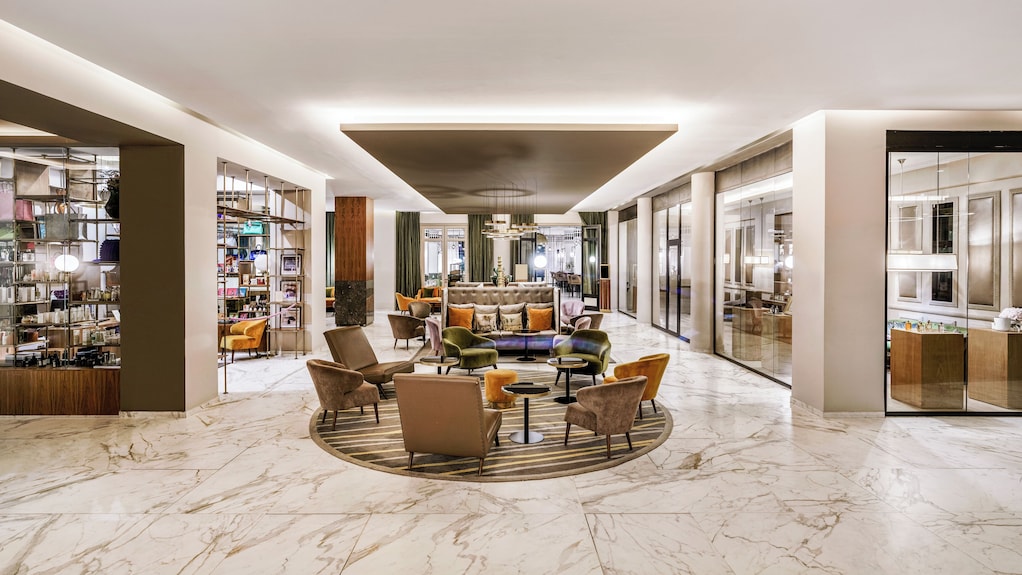 Sofitel Marrakech Palais Imperial & Spa luxury hotel lobby with beige marble floors, modern seating, and glass storefronts