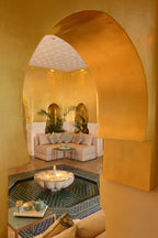 Sofitel Marrakech Palais Imperial & Spa interior featuring a golden yellow Moroccan arch, tiled fountain, beige sofas, and decorative cushions