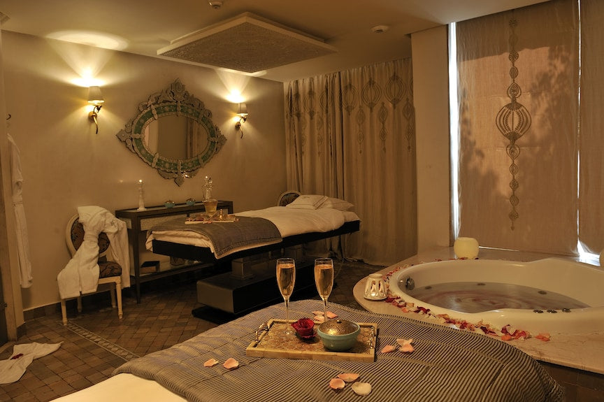 Sofitel Marrakech Palais Imperial & Spa dimly lit spa room with massage table, jacuzzi tub, decorative mirror, and rose petals