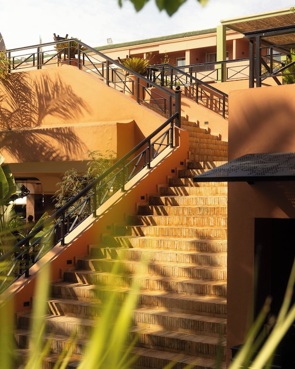 Sofitel Marrakech Palais Imperial & Spa terracotta outdoor staircase with black metal railings surrounded by tropical plants under bright sunlight