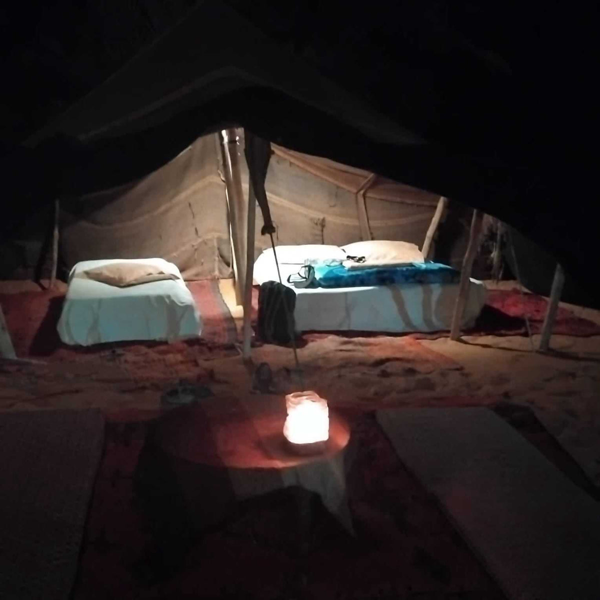 Standard Camp Merzouga Oasis showing traditional desert tent with two single beds and a glowing lantern on a carpeted floor at night