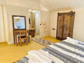 Desert camp interior at Sunset Desert Camps with beige canvas walls, yellow floor, patterned bedspread, and carved wooden furniture.