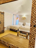 Sunset Desert Camps interior featuring twin beds with white linens, traditional patterned furniture, and warm ambient lighting