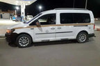 White and black multi-passenger taxi van with gold stripe and tinted windows, ideal for Taxi Rental from Merzouga to Ouarzazate.