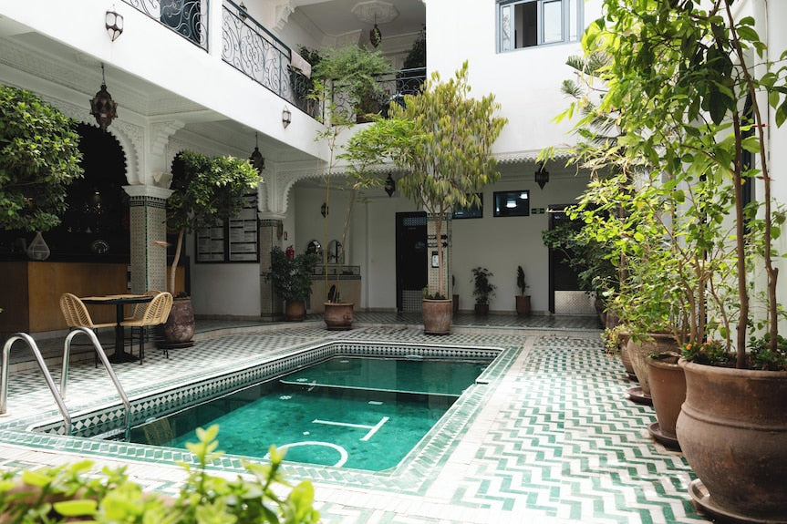 The Central House Marrakech Medina courtyard with turquoise tiled indoor pool surrounded by potted plants and Moroccan architectural details