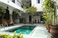 The Central House Marrakech Medina courtyard with turquoise tiled indoor pool surrounded by potted plants and Moroccan architectural details
