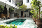The Central House Marrakech Medina courtyard with turquoise tiled indoor pool surrounded by potted plants and Moroccan architectural details