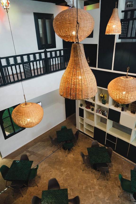 The Central House Marrakech Medina featuring a stylish interior with woven pendant lights, black and white decor, green tables, and chairs